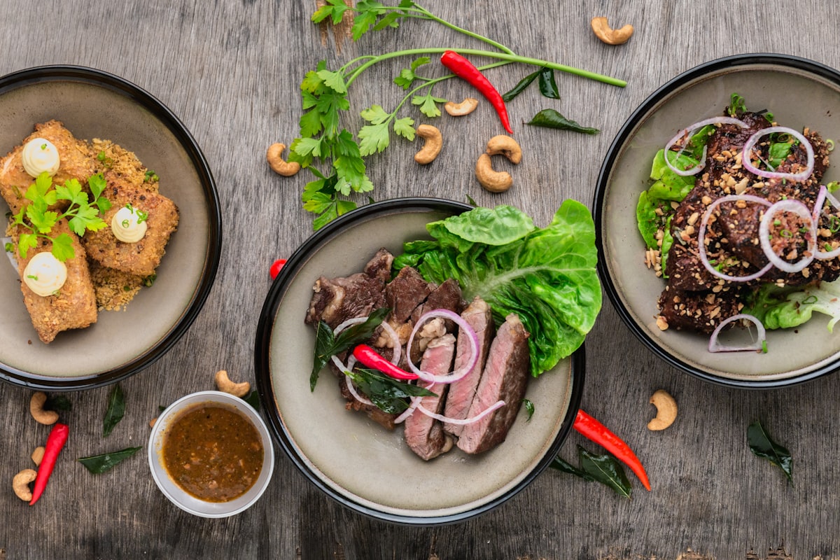 Three plated dishes arranged on weathered wood, seen from above